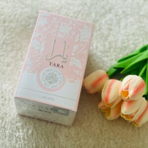 Yara perfume box alongside pink tulips placed on a plush carpet, showcasing elegance and freshness.